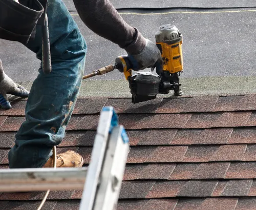Roofer nailing tiles on a shingle roof